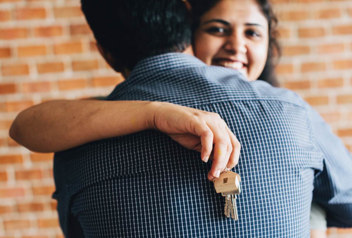 Couple hugging with keys in hand