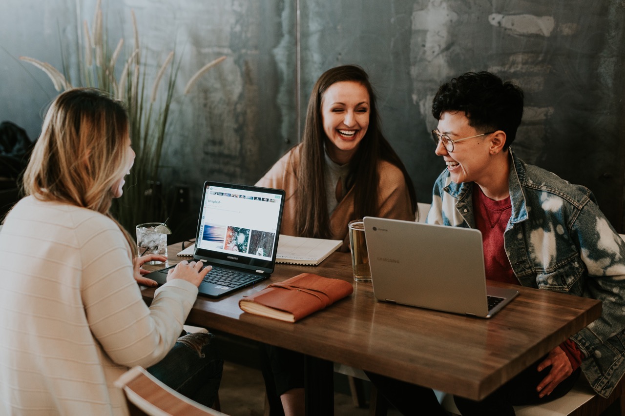 3 people laughing while working on their laptops